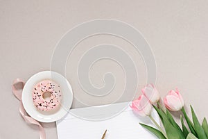 Trendy stylish banner for a female blogger: pink donut, pink tulips and an open Notepad with a clean page on a coffee background