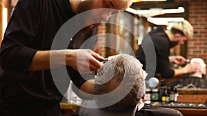 trendy stylish master cuts hair of old man client in modern barbershop