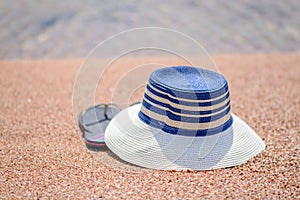 Trendy sunhat and beach thongs on the sand