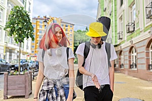 Trendy teenage hipsters boy and girl walking talking on city street