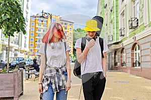 Trendy teenage hipsters boy and girl walking talking on city street