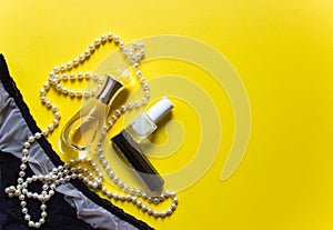 Trendy top view of perfume, nail polish, lip stick, lingerie on yellow background. Beauty product, cosmetic concept. Free copy
