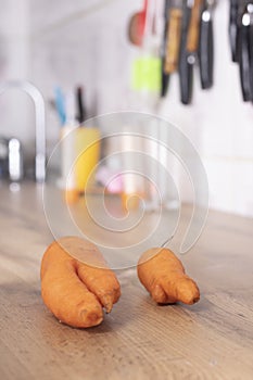 Trendy ugly carrots on worktop in kitchen, blurred background