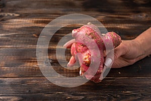 Trendy ugly organic potato from home garden on on a wooden background