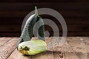 Trendy ugly organic squash and cucumber on dark natural blurred background. Copy space
