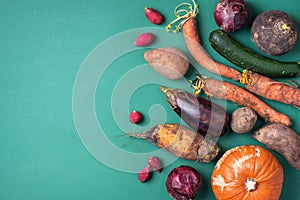 Trendy ugly organic vegetables. Assortment of fresh eggplant, onion, carrot, zucchini on green background. Top view. Cooking ugly