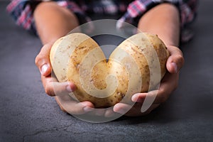 Trendy ugly vegetable heart shaped potato in hands