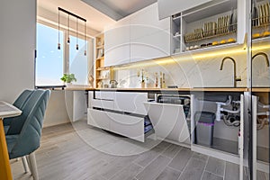 A trendy white kitchen with drawers pulled out to their full length