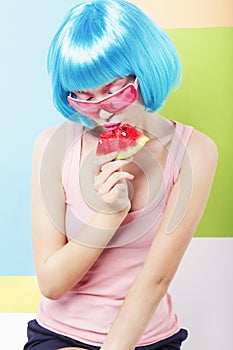 Trendy Woman in Blue Wig and ping Glasses Eating Watermelon