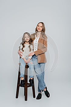 trendy woman embracing daughter sitting on