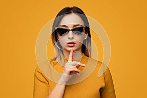 Trendy woman making silence gesture in studio