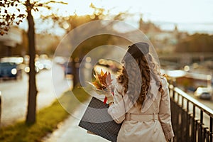 Trendy woman with shopping bags and autumn yellow leaves