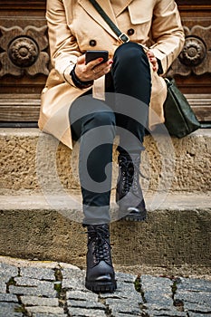 Trendy woman sitting on stairs and using smart phone in city