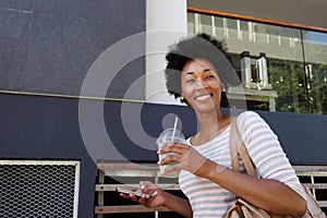 Trendy woman smiling with coffee and cellphone