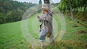 Trendy woman tasting grapes at green vineyard cloudy day. Girl eating berries