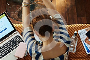 Trendy woman using fan while suffer from heat