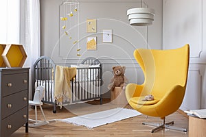 Trendy yellow egg chair in elegant grey nursery