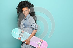 Trendy young black woman holding a skateboard under her arm