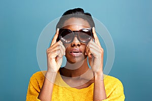 Trendy young black woman in sunglasses by blue wall