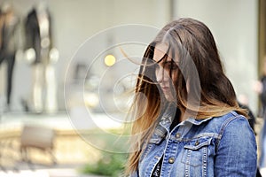 Trendy young hipster woman is looking down sadly with a blowzy hair.