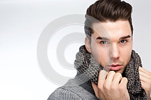 Trendy young man posing with gray wool scarf