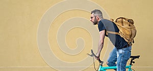 Trendy young man posing on a minimalist bicycle, portrait of a cyclist in an urban context, cycling in the city to go to work with