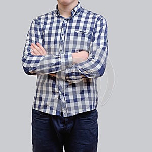Trendy young man wearing blue checkered shirt, standing against a grey background