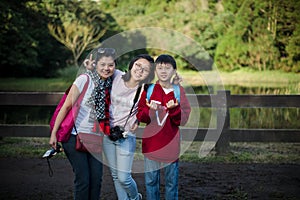 Trendy young mum and two teenagers standing near ranch