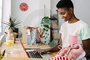 Trendy young small business owner woman working on laptop in office