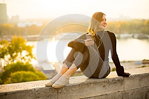 Trendy young woman listening music from smartphone outdoor
