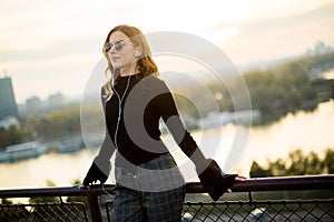 Trendy young woman listening music from smartphone outdoor at sunset