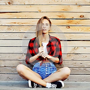 Trendy young woman posing against wooden wall