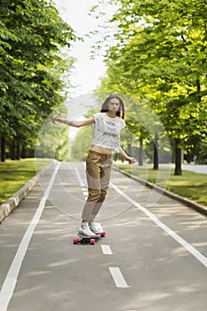 Trendy young woman rides a longboard on a path in a park outdoors in summer. Skateboarding. Outdoors,