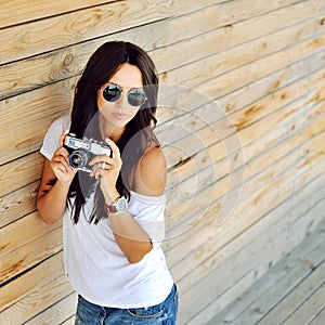 Trendy young woman in sunglasses with old camera outdoor