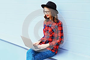 Trendy young woman working using laptop computer outdoors