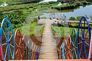 Treppen mit bunten RÃ¤dern als Zaun fÃ¼hren zu einer Holzterasse mit bunten StÃ¼hlen Ã¼ber einen Holzweg in Dalat, Vietnam