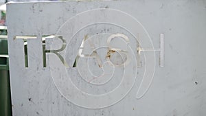 TRESH inscription on iron metal surface. Near green garbage bins photo