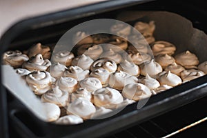 Trey with freshly baked sweet merengues in the oven.Cooking merengues at home. Selective focus. Low DOF