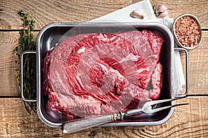 Tri Tip beef steak in steel tray, raw prime meat. Wooden background. Top view