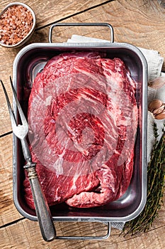 Tri Tip beef steak in steel tray, raw prime meat. Wooden background. Top view