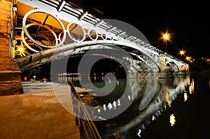 Triana Bridge over Guadalquivir river at sunset with river reflections