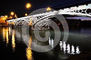 Triana Bridge over Guadalquivir river at sunset with river reflections