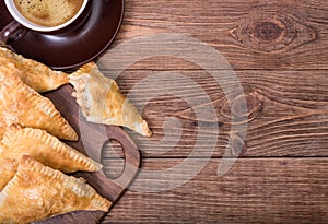 Triangle meat pies with cup of coffee .