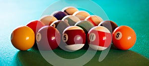 Triangle of multicolored billiard balls with numbers on the pool table. Sports game billiards on a green cloth. Banner