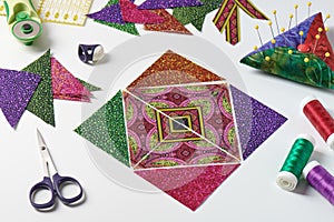 Triangle pieces of fabric laid out in the shape of a patchwork block, sewing and quilting accessories