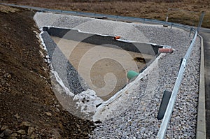 Triangle-shaped drainage pond with stone wall paneling and gabion walls. the water slows down during the rain and then overflows f