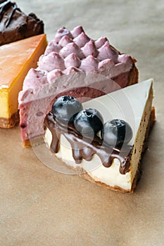 Triangular Cake Pieces Assorted Flavors, Coconut, Chocolate, Orange, Blueberry on kraft paper.