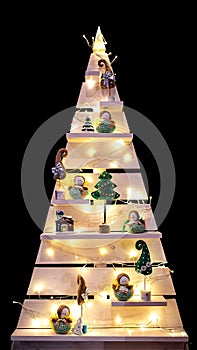 Triangular Christmas tree with shelves and Christmas winter accessories. Isolate on a black background