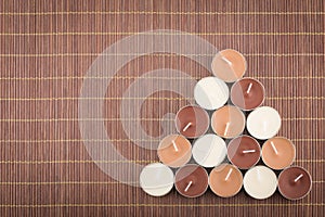 Triangular composition of tea light candles on a bamboo placemat