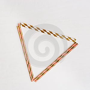 Triangular frame from bright multicolor paper drinking straws with Gold striped on light background